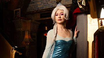 person wearing an Elsa costume with icy blue gown and platinum blonde hair in a vibrant indoor setting 16 years celebration theme winter princess magic