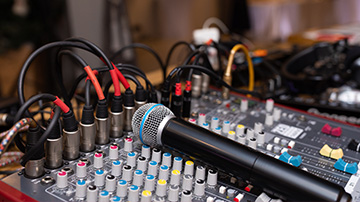 microphone on audio mixing console with cables and knobs featuring sound equipment for live performances and recordings